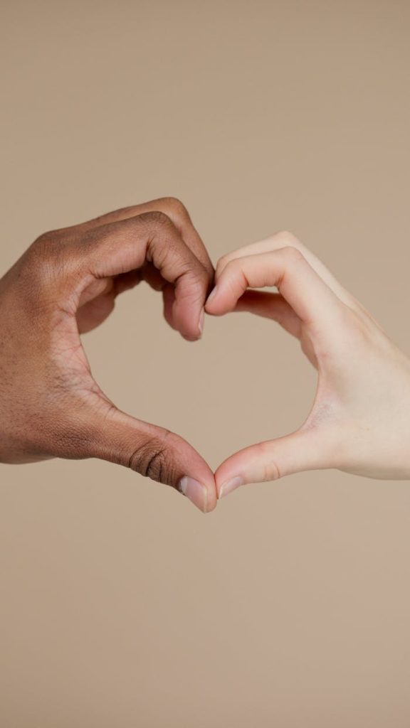 Two hands of different ethnicities form a heart shape, symbolizing unity and diversity.